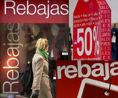 una mujer pasa en frente de una tienda durante las rebajas