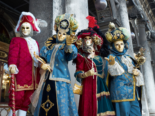 Gente dizfrazada con trajes y máscaras venecianas