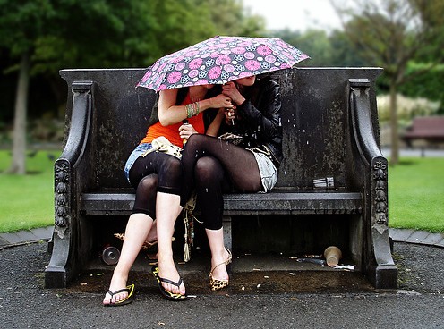 Chicas sentadas bajo la lluvia